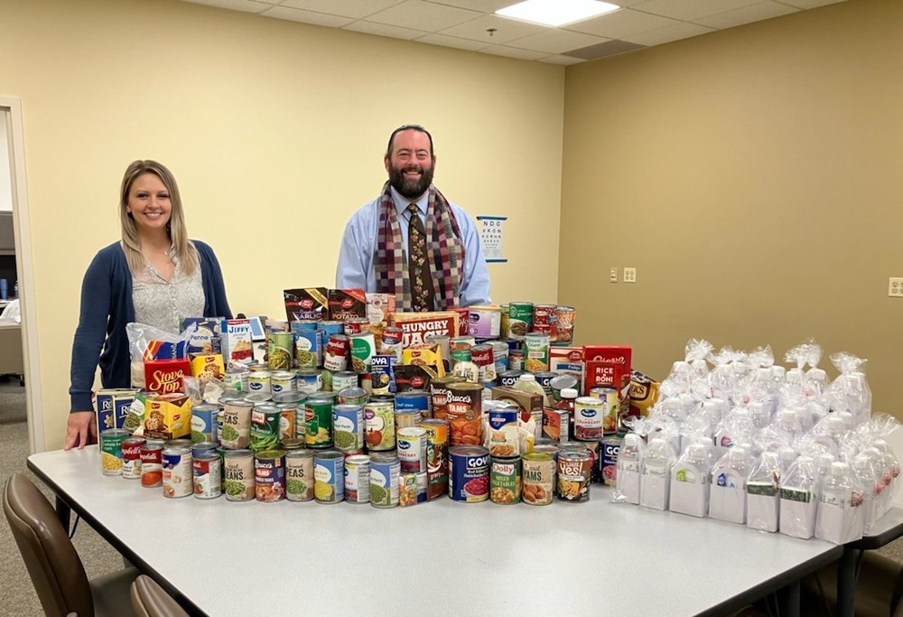 Principal Dr Osborn and Mrs Argiro from the main office stand with the compiled donated canned goods and care packages